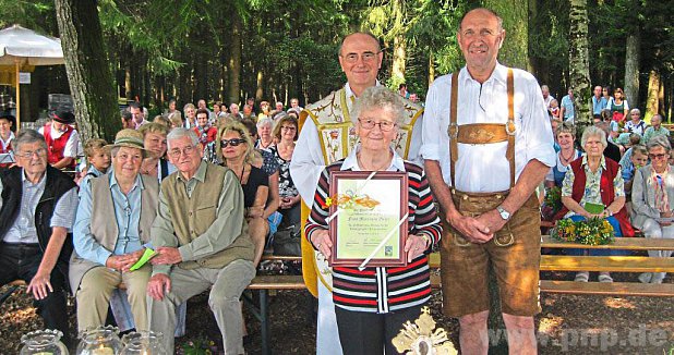 Im Rahmen der Waldmesse nahmen Pfarrer Jakob Krowiak (links) und Kirchenpfleger Johann Krumbachner (rechts) die Ehrung von Marianne Geier vor. − Foto: Heckmann