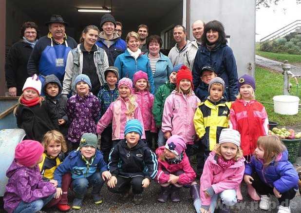 Zusammen mit einigen Eltern freuen sich die Kinder über den Apfelsaft, den die Mitglieder des Gartenbauvereins Brigitte Salzinger und Willi Stolz (hinten von links), sowie Anna Engelsperger und Franz Riedelsheimer (hinten 4. und 5. von rechts) aus den gespendeten Äpfel gepresst hatten. − Foto: Eichinger